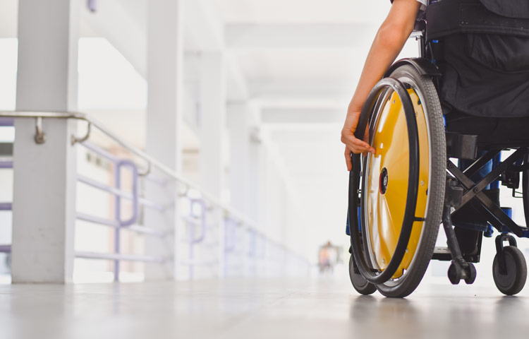 Close up photo of child sitting on the wheelchair in hospital walk way