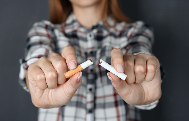 Woman breaking cigarette, stock photo