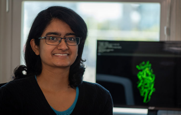 Mallika Iyer in front of computer with green protein