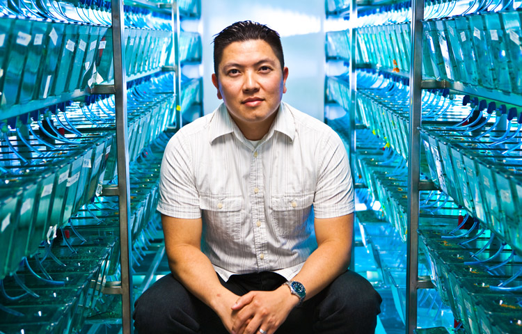 Associate professor Duc Dong, PhD seated in front of blue laboratory equipment