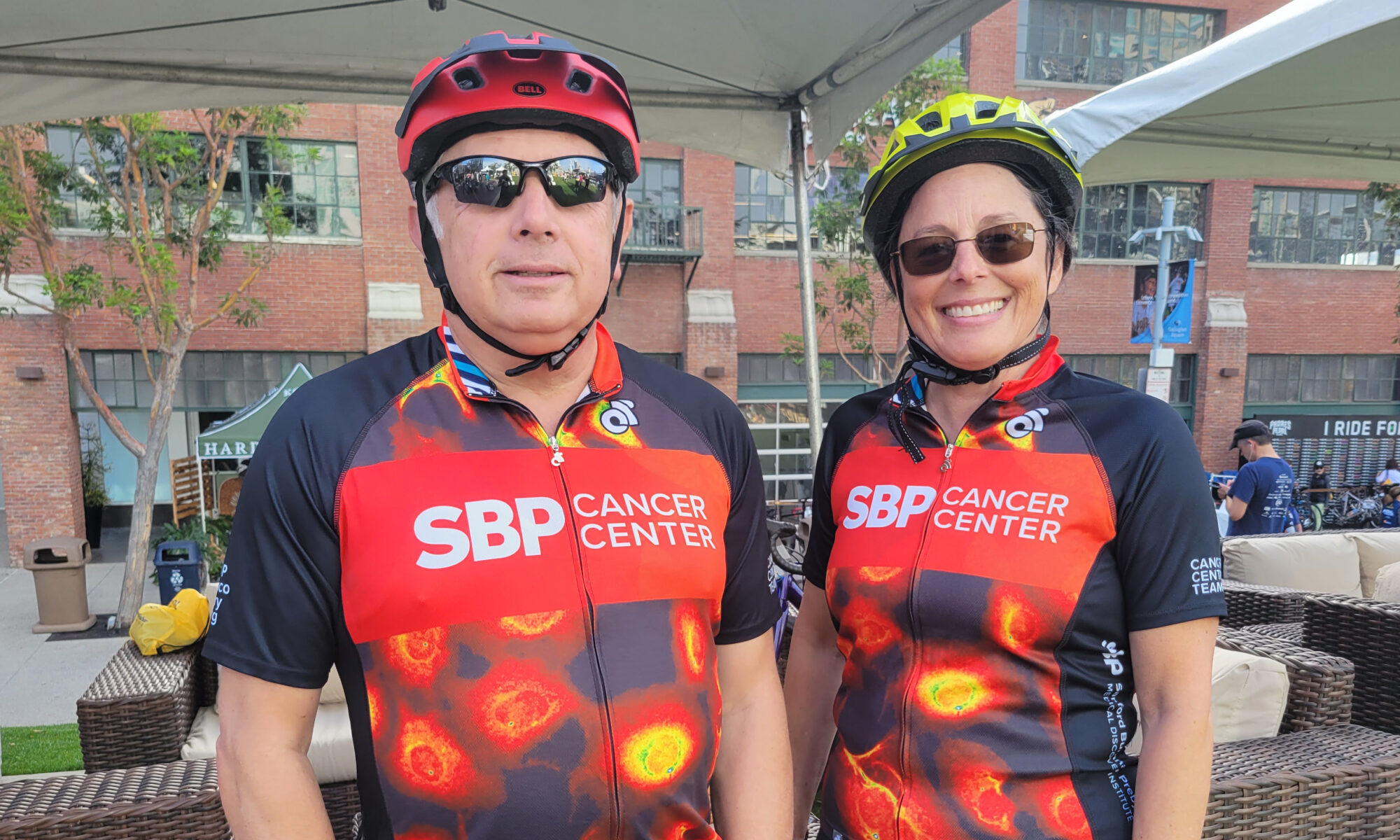 Ze'ev Ronai and Adrienne Crown in biking outfits with Sanford Burnham Prebys branding