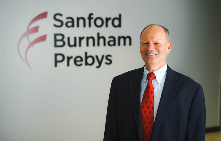 David Brenner, MD, in front of Sanford Burnham Prebys logo on wall