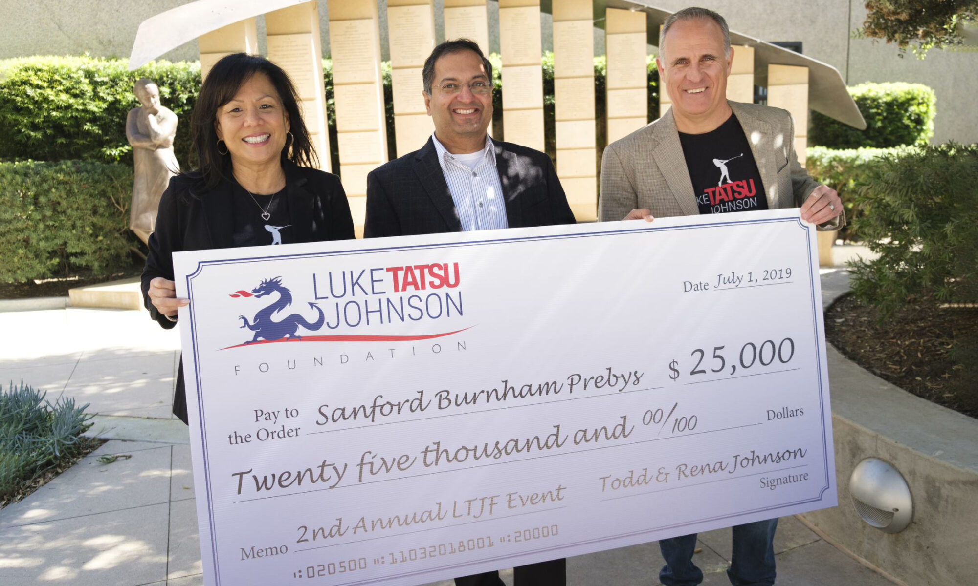 Rena Johnson, Ani Deshpande, PhD, and Todd Johnson holding a large cardboard check for $25,000 from the Luke Tatsu Johnson Foundation