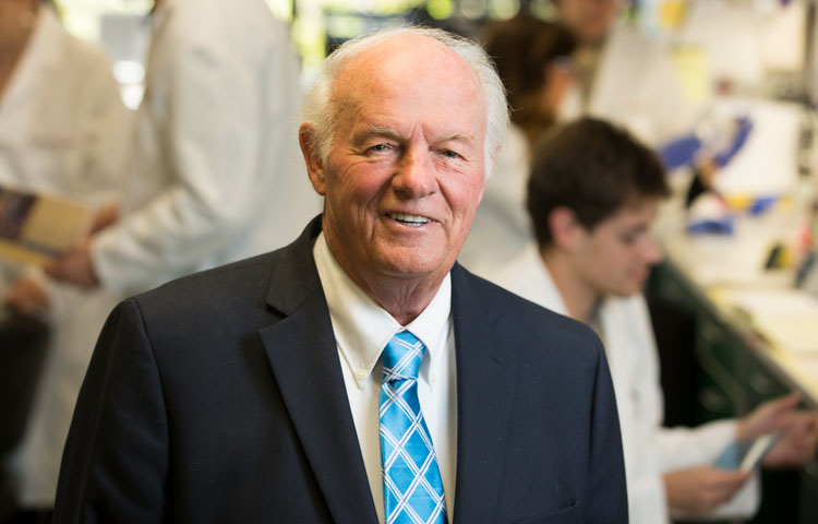 Denny Sanford in the lab with scientists working in the background