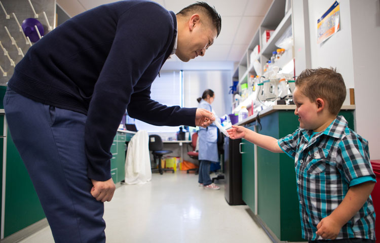 Duc Dong in the lab talking with a young child