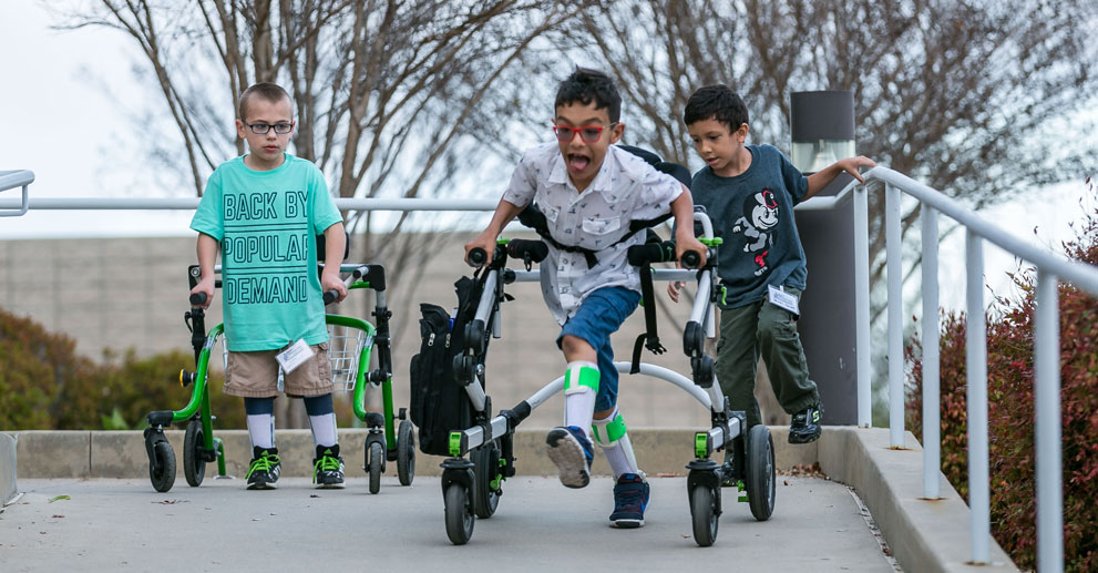 children with walkers playing on handicap ramp