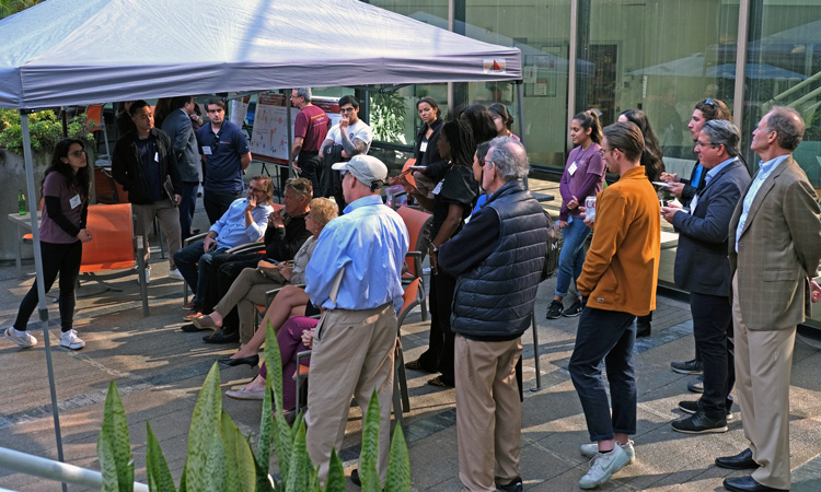 crowd listens to poster presentation at March 2024 Cancer Center Open House