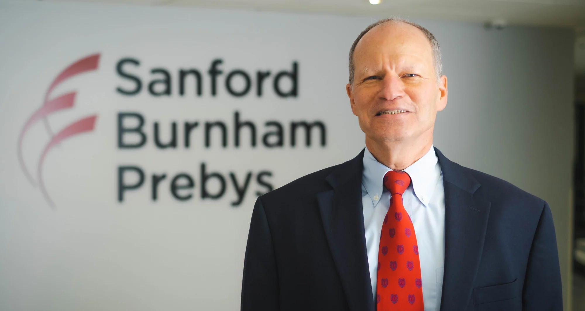 David Brenner standing in front of Sanford Burnham Prebys logo