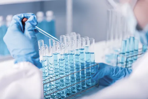 cientist hand dropping chemical liquid into test tube,