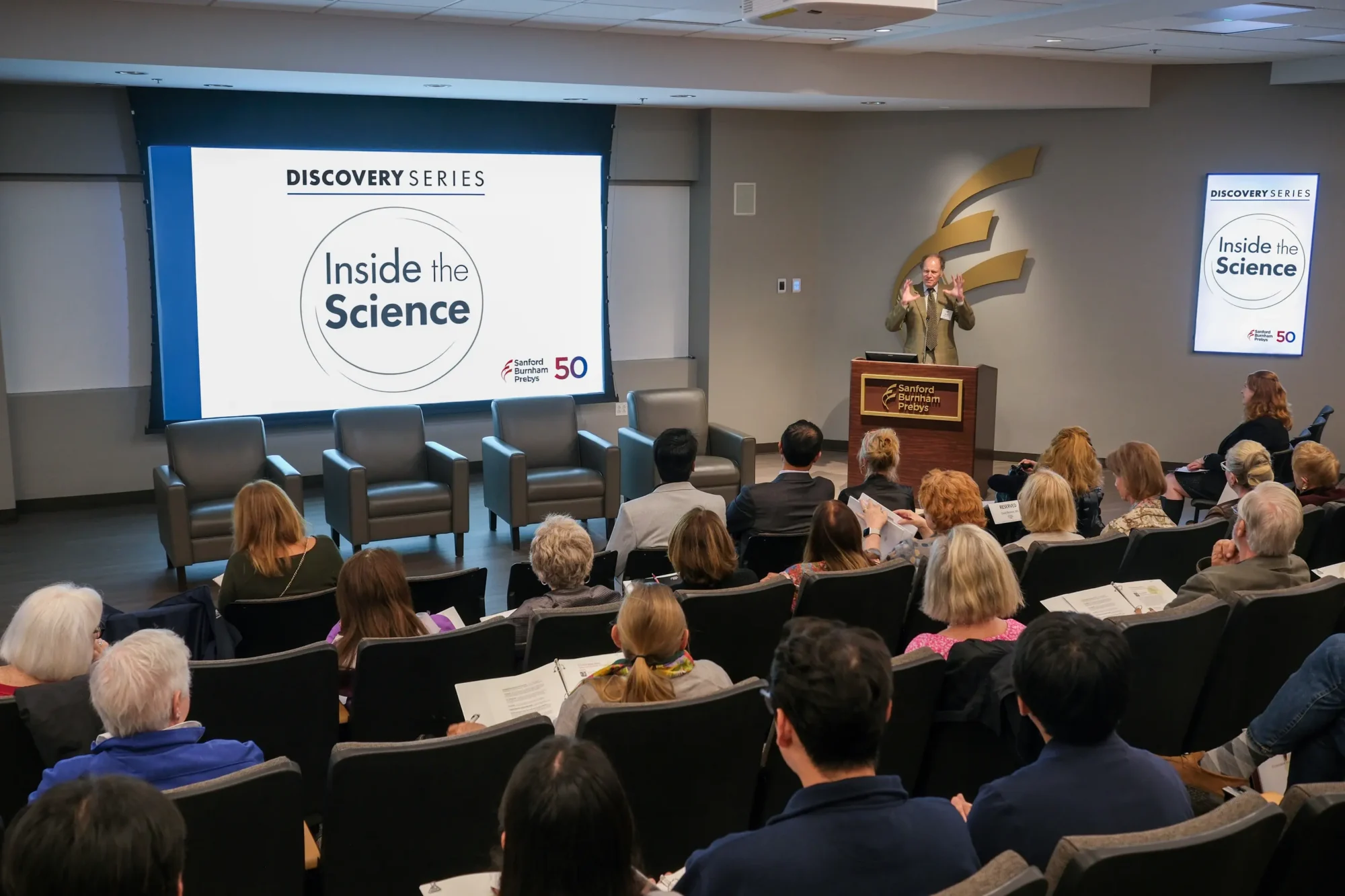 David Brenner speaking at podium in LaFave auditorium